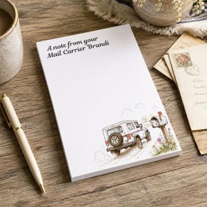 May include: A white rectangular notepad featuring the printed text A note from your Mail Carrier Brandi at the top. The bottom right corner displays a colorful illustration of a white mail delivery vehicle parked near a mailbox with flowers.