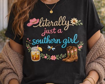 May include: Black t-shirt with the embroidered phrase "literally just a southern girl." The design includes a pink cowboy hat, flowers, a glass of iced tea, a dragonfly, and cowboy boots.