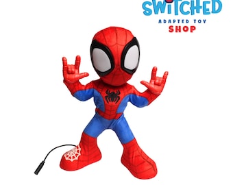 Peut inclure: Peluche Spider-Man rouge et bleu avec un emblème d'araignée noire sur la poitrine. La figurine a de grands yeux blancs et fait un geste de la main. L'image comprend le texte "Switched Adapted Toy Shop".