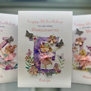 May include: A handmade birthday card with a purple letter E decorated with flowers, butterflies, and glitter. The letter E is surrounded by a watercolor floral design. The card says "Happy 6th Birthday to a very special Granddaughter" and is signed "Evelyn".