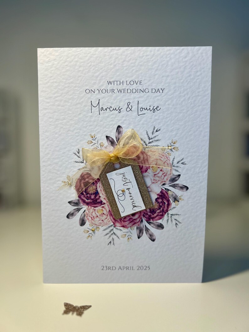 May include: A white wedding card with a floral design and a gold tag that says "just married". The card is addressed to Marcus & Louise and the date is 23rd April 2025.