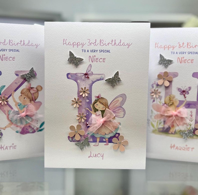 May include: Three handmade birthday cards featuring a watercolor illustration of a fairy with a purple letter and pink flowers. The cards say "Happy 3rd Birthday to a very special Niece" and include the names "Katie", "Lucy", and "Harriet".