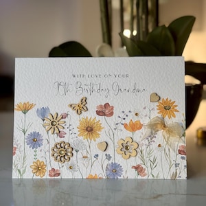 May include: A white card with a floral design and the text "With love on your 80th Birthday Grandma". The card has wooden flowers and hearts.