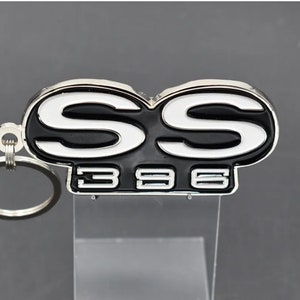 Peut inclure: Un porte-clés en métal argenté et noir avec les lettres "SS" et le numéro "396" dessus.