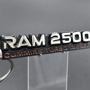 May include: A black and silver metal keychain with the words "RAM 2500 CUMMINS TURBO DIESEL" in red lettering.