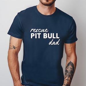 May include: A navy blue t-shirt with the text "rescue PIT BULL dad" in white.