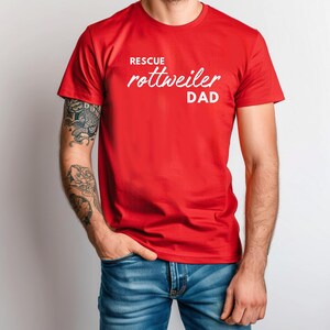 K&ouml;nnte beinhalten: Ein rotes T-Shirt mit dem Text "Rescue Rottweiler Dad" in Wei&szlig;.