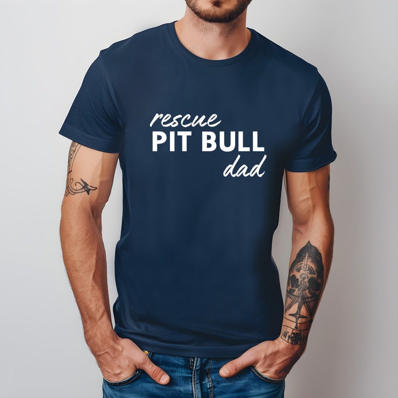 May include: A navy blue t-shirt with the text "rescue PIT BULL dad" in white.