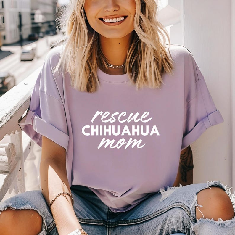 May include: A woman wearing a lavender t-shirt with the text "rescue chihuahua mom" in white.