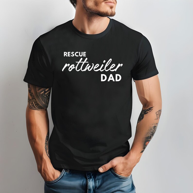 K&ouml;nnte beinhalten: Ein schwarzes T-Shirt mit wei&szlig;em Text, der "Rescue Rottweiler Dad" lautet.