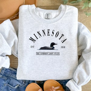 May include: Gray sweatshirt with a black graphic design that says "Minnesota Est. 1858 The Common Loon State" with a black loon illustration.