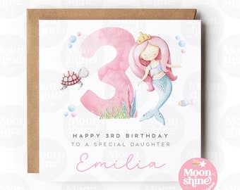 Puede incluir: Una tarjeta de cumpleaños rosa y blanca con una ilustración de sirena y el número 3. La tarjeta dice "Feliz cumpleaños número 3 a una hija especial Emilia".
