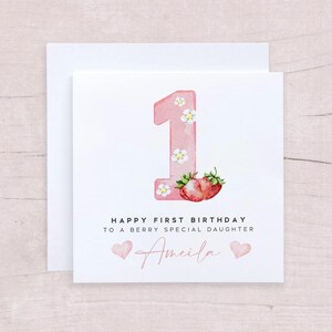 May include: Pink and white birthday card with a number one, strawberries, and the text "Happy First Birthday to a Berry Special Daughter Amelia".