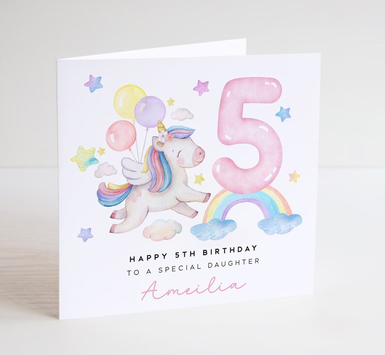 May include: A pink and white unicorn with a rainbow and a pink number 5. The unicorn is holding balloons and flying in the air. The text says "Happy 5th Birthday to a special daughter Amelia".