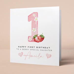 May include: Pink birthday card with a large pink number one decorated with white flowers and two red strawberries. The card says "Happy First Birthday to a Berry Special Daughter Amelia".