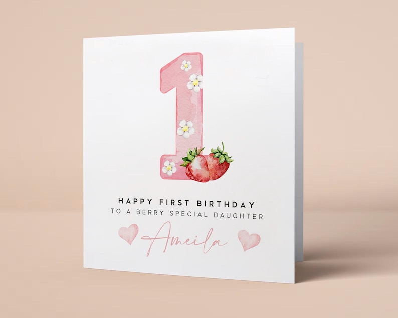 May include: Pink birthday card with a large pink number one decorated with white flowers and two red strawberries. The card says "Happy First Birthday to a Berry Special Daughter Amelia".