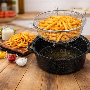 Peut inclure: Un panier en treillis métallique rempli de frites dorées est placé au-dessus d'une marmite noire mouchetée d'huile chaude. Une planche de bois avec plus de frites et de petits bols de condiments sont sur une surface en bois.