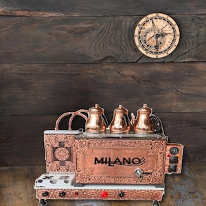 May include: Copper Turkish coffee maker with ornate detailing and the word "MILANO" on the front. The coffee maker has four individual copper pots and a burner with multiple knobs.