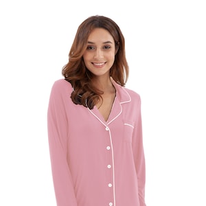 May include: A pink pajama set with long sleeves and pants. The top has a white collar and white piping around the edges. The top has a button-up front.