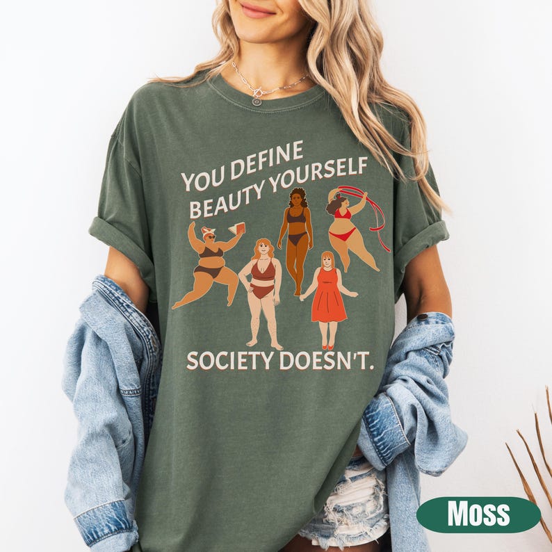 K&ouml;nnte beinhalten: Gr&uuml;nes T-Shirt mit dem Text "You define beauty yourself. Society doesn't." und einer Illustration von sechs Frauen mit unterschiedlichen K&ouml;rperformen und Hautt&ouml;nen.
