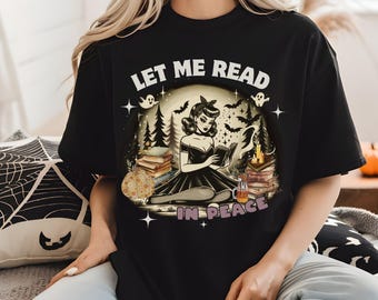 May include: Black t-shirt with a graphic of a woman reading a book in a spooky forest setting. The text "Let me read in peace" is printed on the shirt.