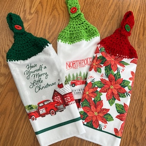 May include: Three Christmas-themed kitchen towels with crocheted tops. One towel has the text "Have yourself a Merry Little Christmas" with a red truck graphic. Another says "Northpole Tree Farm" with a red truck. The third has red poinsettias.