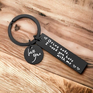 May include: Black metal keychain with a round charm that says "love you" and a rectangular charm that says "Drive safe. I need you here with me."