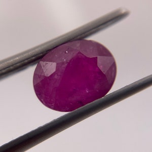 May include: A vibrant pink oval-shaped gemstone with a faceted cut.
