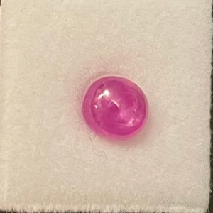 Può includere: Una pietra preziosa ovale di colore rosa con una superficie liscia e lucida.