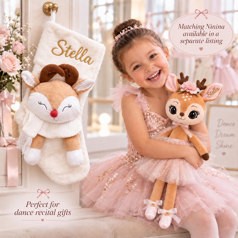 Op de afbeelding: Een witte kerstkous van imitatiebont met de geborduurde naam Stella, voorzien van een pluche rendier met een rode neus en witte sjaal. De kous wordt getoond naast een pluche rendierpop die een roze tutu en balletschoentjes draagt.