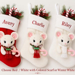 Op de afbeelding: Drie kerstsokken met pluche witte muizen met roze oren. E&eacute;n sok is rood, twee zijn wit. Elke sok heeft een witte boord met de namen Avery, Charlie of Riley. De muizen dragen sjaals en houden zuurstokken vast.