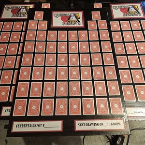 May include: Arrangement of playing cards, likely for a game, with the words "Queen of Hearts" displayed. The cards are red with white circular designs. The game boards have text that says "Current Jackpot" and "Next Drawing".