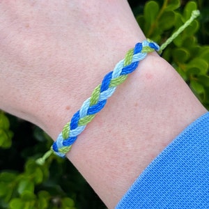 May include: A braided friendship bracelet with blue, light blue, and green threads.