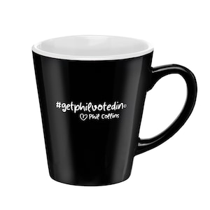 May include: Black ceramic coffee mug with a white interior and a white handle. The mug has a white graphic that says "#getphilvotedin" with a heart and "Phil Collins" underneath.
