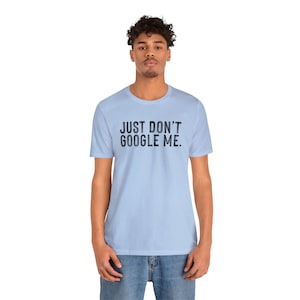 Può includere: Una t-shirt blu chiaro con la scritta "JUST DON'T GOOGLE ME." stampata in nero.