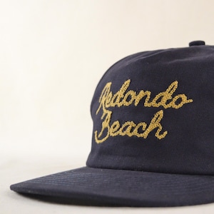 Puede incluir: Gorra de b&eacute;isbol azul marino con la inscripci&oacute;n bordada "Redondo Beach" en letras doradas. La gorra tiene una visera curva y una corona estructurada, ideal para protegerse del sol.