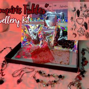 May include: A black box filled with various jewellery making supplies, including beads, charms, and chains. The box is labelled "Vampiric Fables" Jewellery Kit. The image also shows a variety of silver charms with vampire and gothic themes, including bats, crosses, and moons.