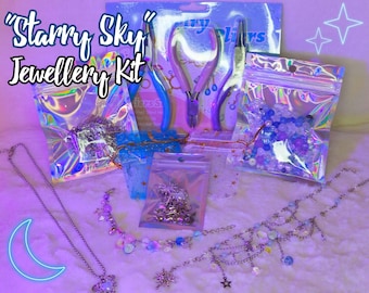 May include: A "Starry Sky" Jewellery Kit with various jewelry-making supplies. The kit includes pliers, beads, chains, and charms in shades of blue, purple, and silver. The image features a necklace with a moon pendant and other celestial-themed jewelry.
