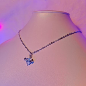 Op de afbeelding: Een zilveren ketting met een klein, helder kristallen hanger in de vorm van een hart. De hanger heeft een zilveren halo eromheen.