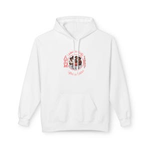 Op de afbeelding: Witte hoodie met een voorzak en een trekkoord. De hoodie heeft een cirkelvormige afbeelding met de letters AKM en de woorden "United in Sisterhood" en "Lifted in Sisterhood" in het rood.