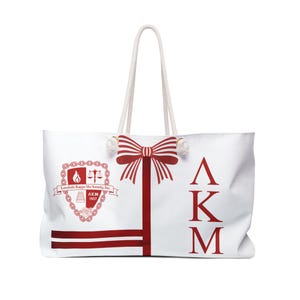 Op de afbeelding: Witte draagtas met rode accenten en touwhandvatten. Voorzien van een rode strik, de Griekse letters ΛKM en een wapen met de tekst "Lambda Kappa Mu Sorority, Inc. AKM 1937".
