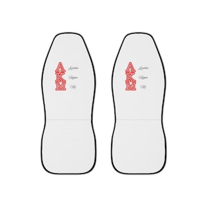 May include: Pair of white car seat covers with black trim. Each cover features the Greek letters AKM in red, with the words Lambda, Kappa, and Mu in black. The seat covers are designed to fit most car seats.