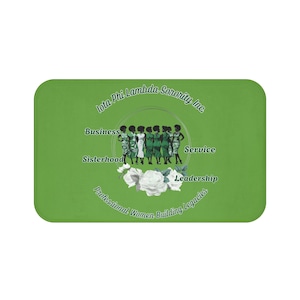 Pode incluir: Um tapete retangular verde com o texto "Iota Phi Lambda Sorority Inc." e as palavras "Business, Sisterhood, Service, Leadership". O tapete também inclui uma ilustração de mulheres e rosas brancas.