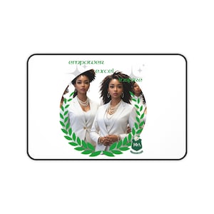 Può includere: Tappetino per mouse bianco con una grafica di tre donne in abiti bianchi e collane di perle, incorniciata da una corona d'alloro verde. Le parole "empower, excel, inspire" sono scritte sopra l'immagine. Il logo IFA è in basso.