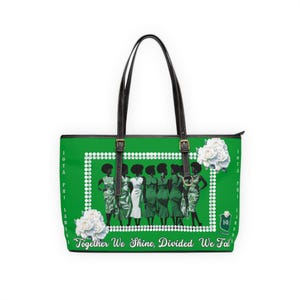 Op de afbeelding: Groene tote bag met zwarte handvatten en riemen. De tas heeft een wit frame met een groep vrouwen in jurken. De tekst "Together We Shine, Divided We Fall" staat onderaan.