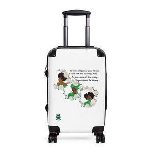 May include: White rolling suitcase with a black handle and wheels. The suitcase features an illustration of three women surrounded by white flowers and text that reads "She moves with purpose, speaks with care..."