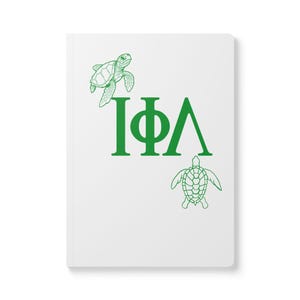Pode incluir: Caderno branco com ilustrações de tartarugas verdes e as letras gregas I, Φ e Λ. As tartarugas são desenhadas em um estilo de linha detalhado. O caderno tem um design limpo e minimalista.