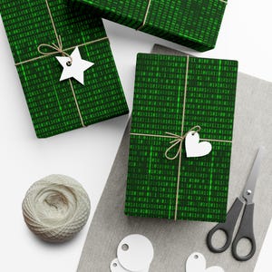May include: Three green gift boxes wrapped in binary code wrapping paper with white string and gift tags. The gift tags are shaped like a star and a heart.