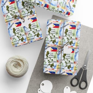 May include: Gift-wrapped boxes with Philippines map-themed wrapping paper, tied with twine and adorned with heart-shaped tags. A spool of twine, scissors, and blank tags are also present, suggesting a DIY gift-giving theme.
