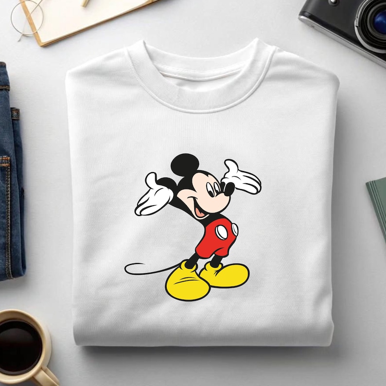 May include: White sweatshirt featuring a colorful graphic of Mickey Mouse. The cartoon character is depicted with black ears, a black head, white gloves, red shorts, and yellow shoes. The sweatshirt is a crew neck style.